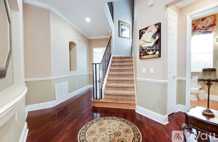 A large, well-lit foyer with a staircase and a rug.
