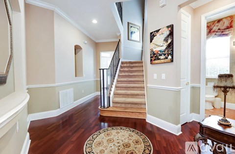 A large, well-lit foyer with a staircase and a rug.