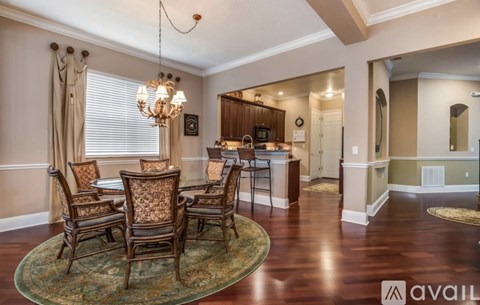 A dining room with a chandelier, a table with chairs, and a mirror on the wall.