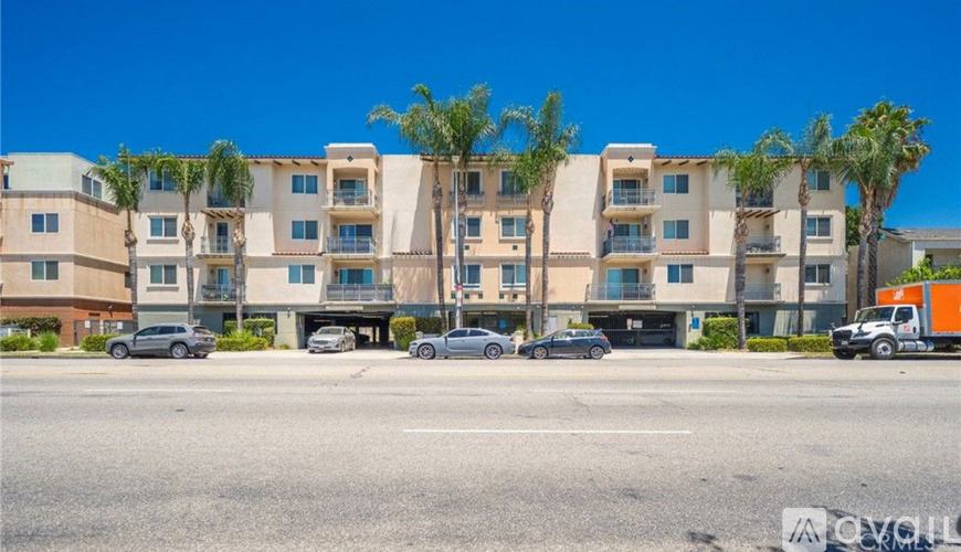 A row of apartment buildings with cars parked in front.