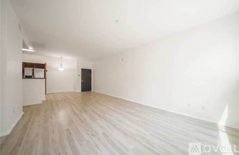 A spacious room with wooden flooring and white walls.