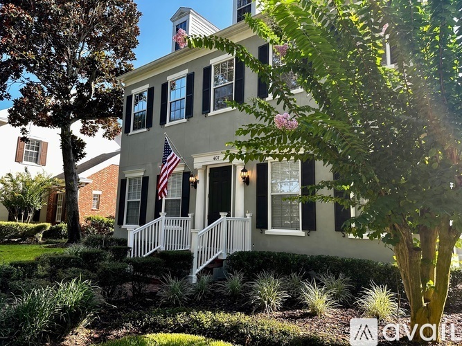 A white house with a black front door and a flag on the porch.