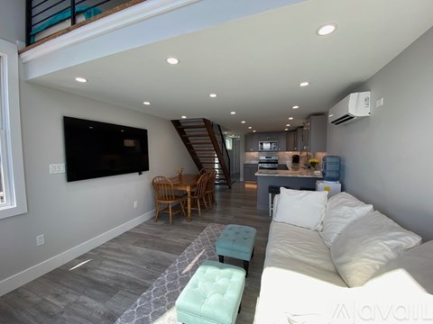 A living room with a couch, a chair, and a television on the wall.