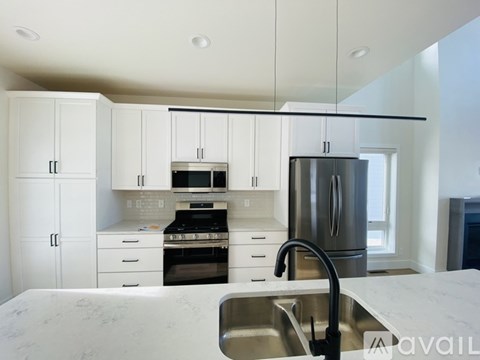 A modern kitchen with white cabinets and stainless steel appliances.