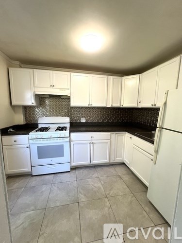 A kitchen with white cabinets and a black countertop.