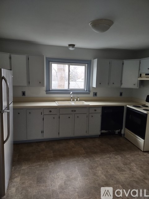 A kitchen with white cabinets and a window.