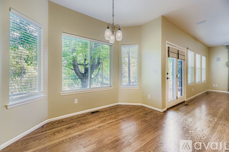 A room with wooden floors and a large window with blinds.