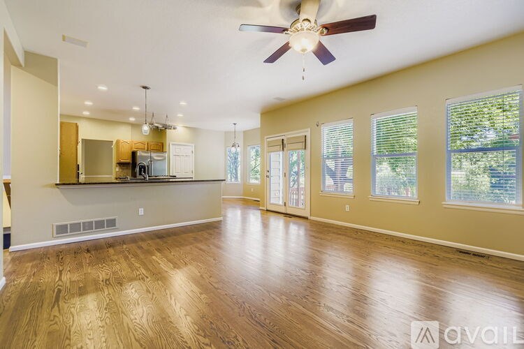 A spacious living room with hardwood floors and a ceiling fan.