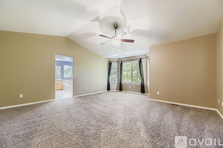 A spacious room with a ceiling fan and carpeted floor.