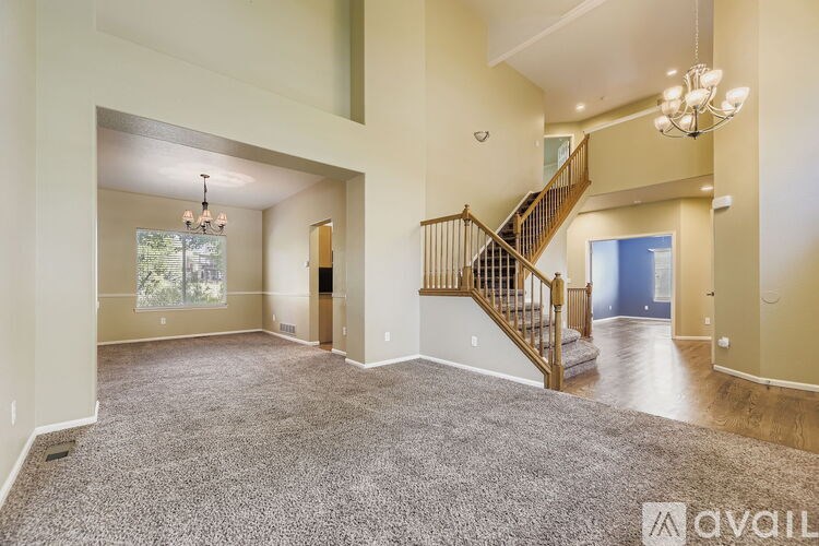 A spacious living room with a staircase and a chandelier.
