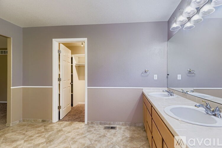 A bathroom with a sink, mirror, and lighting fixture.
