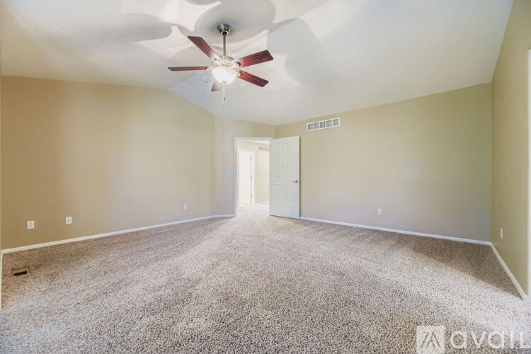 A room with a carpet floor and a ceiling fan.