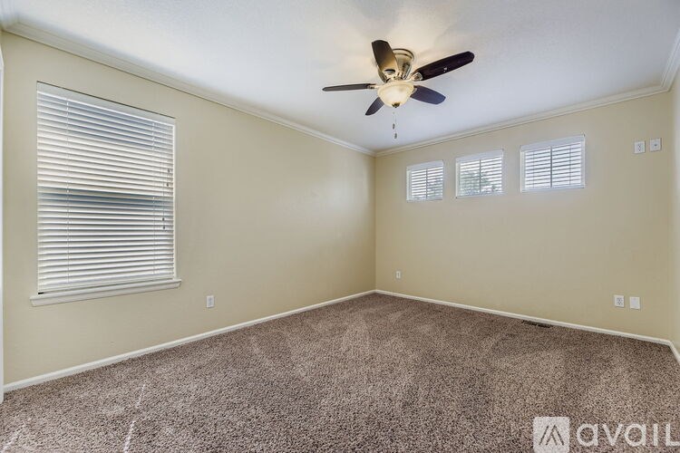 A room with a ceiling fan and carpeted floor.