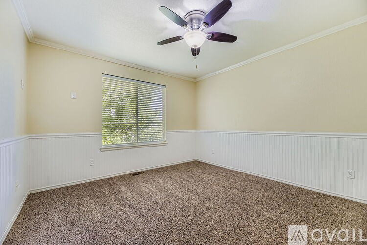 A room with a ceiling fan and carpeted floor.