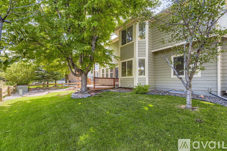 A house with a green lawn and trees in front.