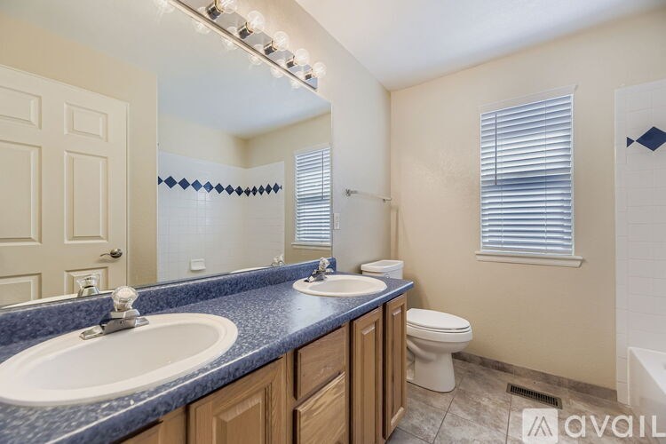 A bathroom with a sink, toilet, and a window with blinds.