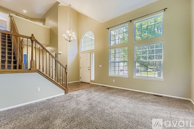 A spacious living room with a staircase and large windows.