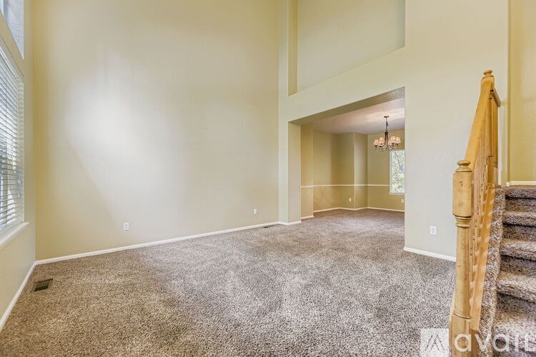 A living room with a carpeted floor and a staircase.