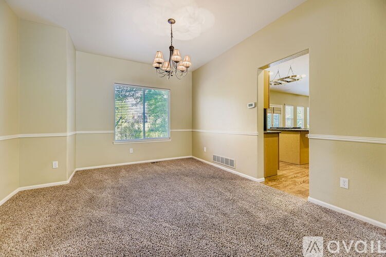 A room with a carpeted floor and a chandelier hanging from the ceiling.