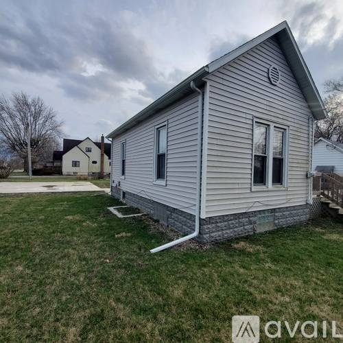 A small house with a grey siding and a white door is available for rent.