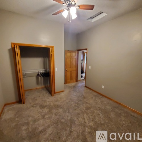 A room with a ceiling fan and a large open door.