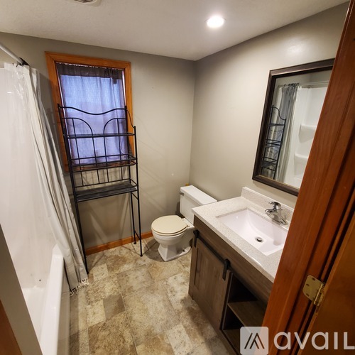 A bathroom with a toilet, sink, and a window with a metal grate.