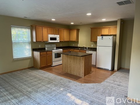 A kitchen with a white refrigerator and wooden cabinets.