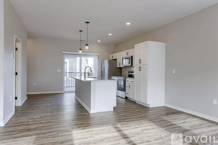 A spacious kitchen with white cabinets and a wooden floor.