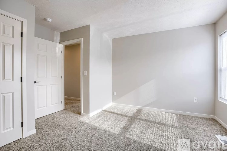 A room with a carpeted floor and a doorway leading to another room.