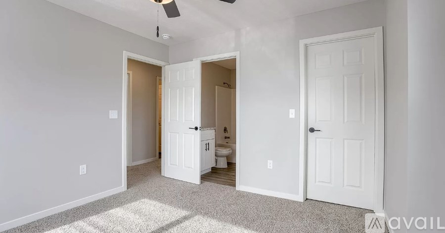 A room with a carpeted floor and a ceiling fan.