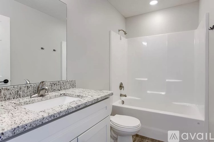 A bathroom with a marble countertop and white fixtures.
