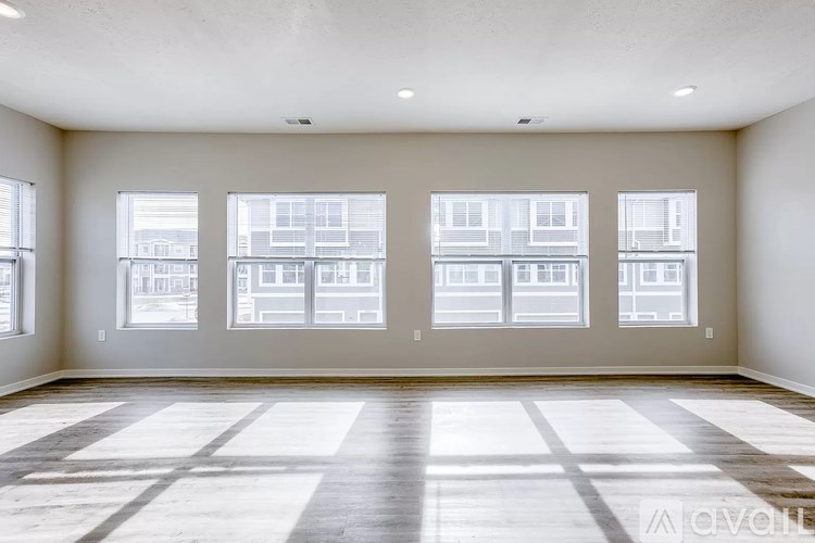 A large empty room with wooden floors and three windows.
