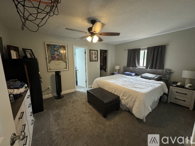 A bedroom with a bed, dresser, and ceiling fan.