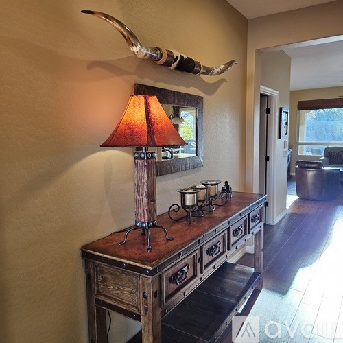 A wooden table with a lamp and candles on it.
