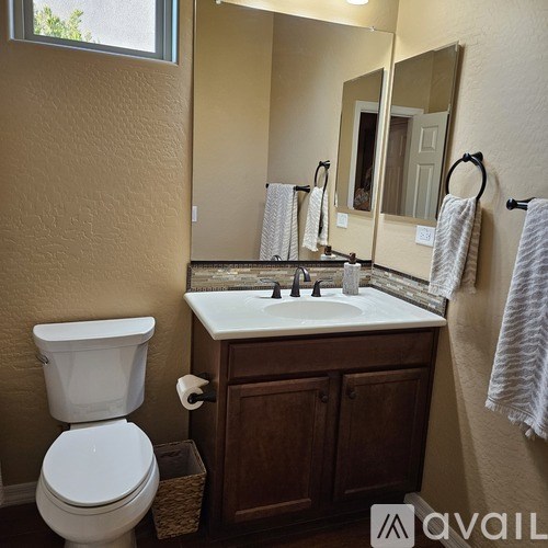 A bathroom with a toilet, sink, and mirror.