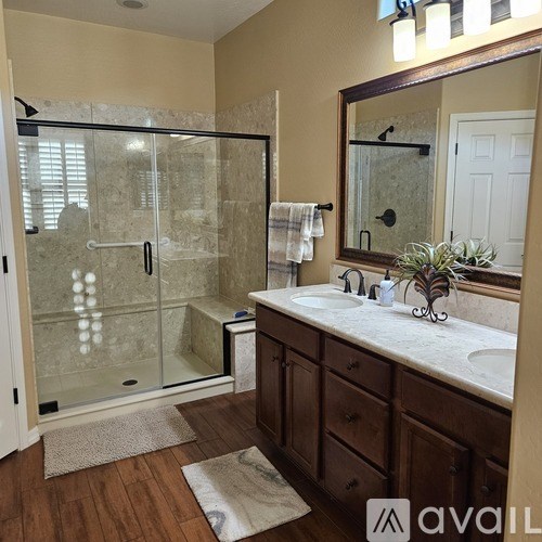 A bathroom with a glass shower door and a marble countertop.