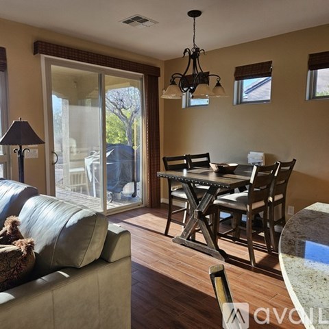 A living room with a grey couch and a dining table with chairs.