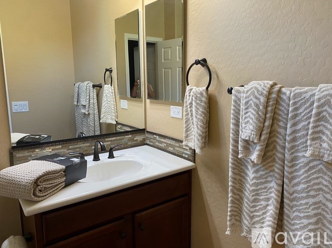 A bathroom with a sink, mirror, and towel rack.