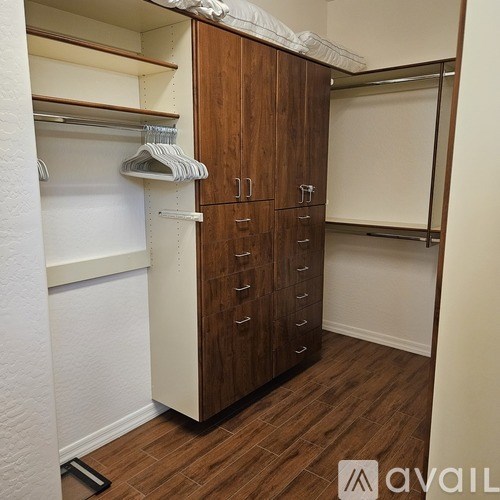 A wooden wardrobe with white shelves and drawers.