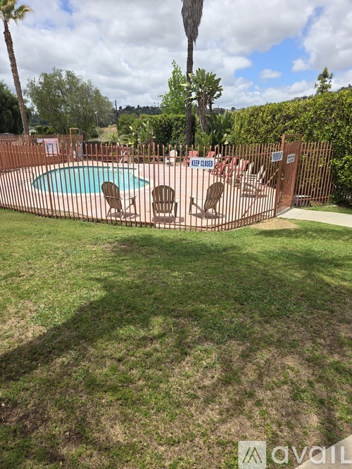 A pool surrounded by a fence and palm trees.