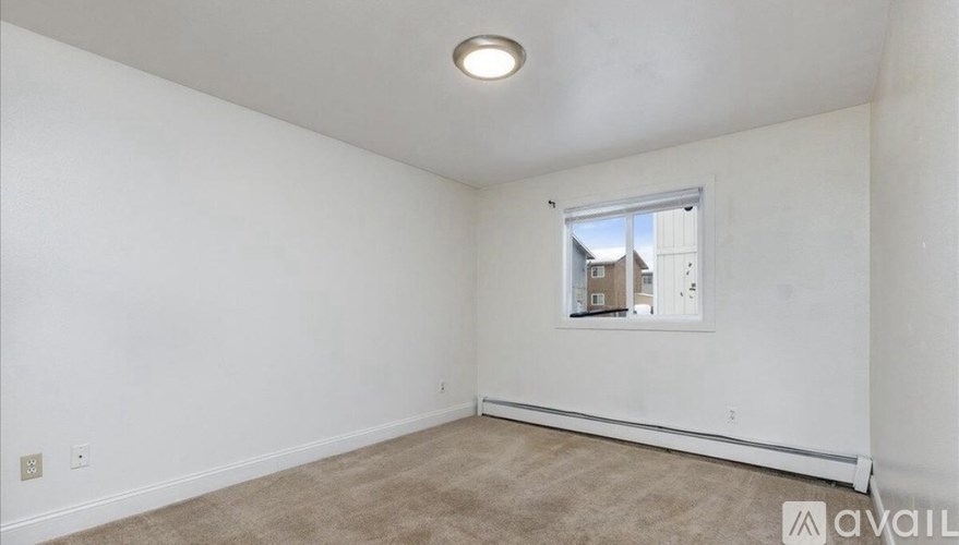 A room with a carpeted floor and a window showing a view of a building outside.