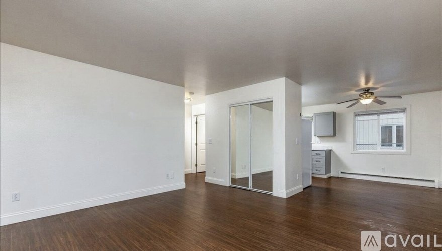 A spacious room with wooden floors and a ceiling fan.