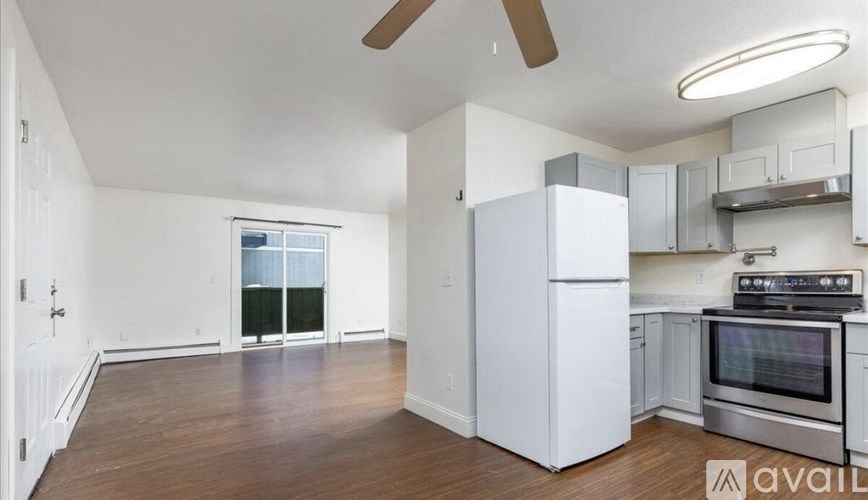 A kitchen with white appliances and a wooden floor.