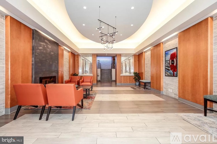 A spacious hallway with orange chairs and a staircase in the background.