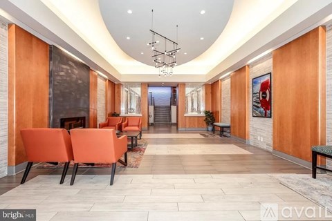 A spacious hallway with orange chairs and a staircase in the background.