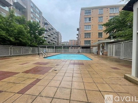 A pool surrounded by a tiled patio in a residential area.