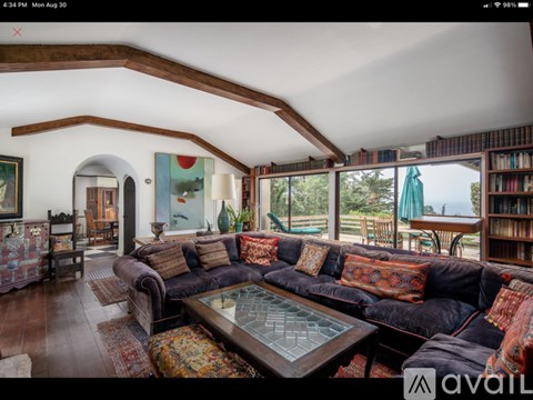 A living room with a large couch and a glass coffee table.