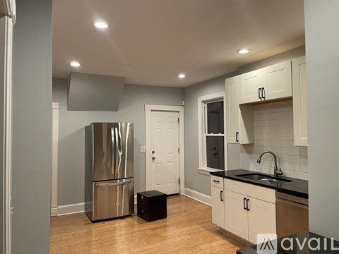 A kitchen with a stainless steel refrigerator and wooden floors.