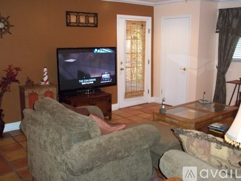 A living room with a grey couch and a television on.