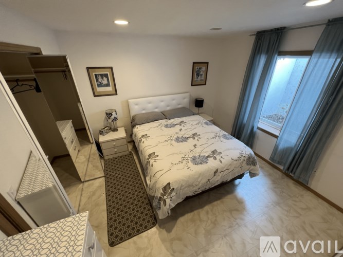 A bedroom with a large bed and a window with curtains.